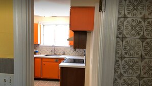 A kitchen with orange cabinets, a white countertop, and patterned backsplash tiles. - Cozy Mediterranean Escape  (Schenectady)