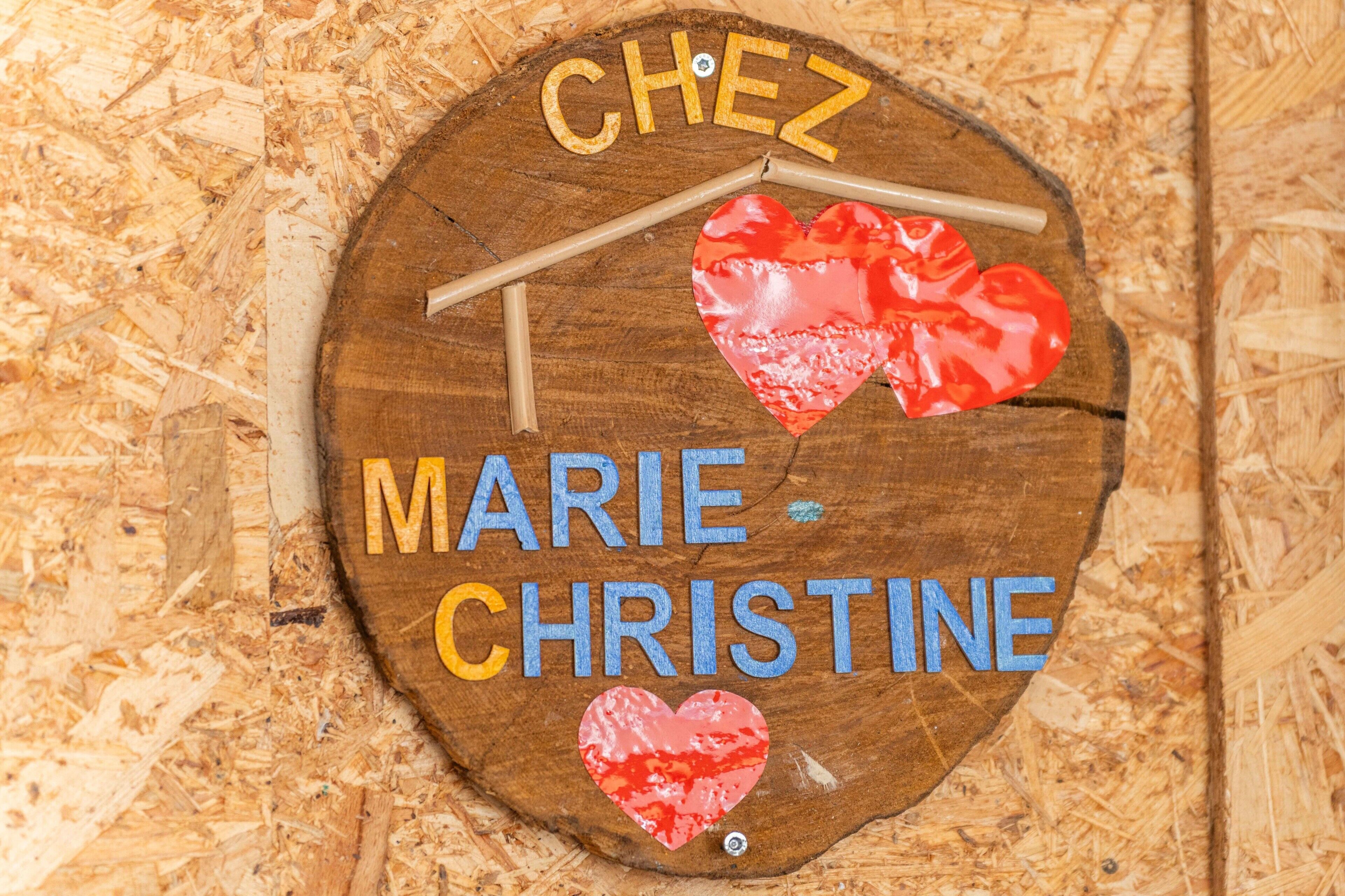 A wooden sign with the names 'CHEZ MARIE CHRISTINE' and two red hearts.