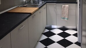 A compact kitchen with a black and white checkered floor, white cabinets, and a window above the sink.