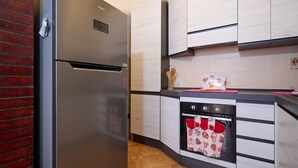 Eine Küche mit einem Edelstahl-Kühlschrank, weißen Schränken, einer schwarzen Arbeitsplatte und einer gefliesten Rückwand.