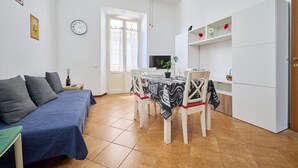 Ein Zimmer mit einem Bett, einem Esstisch mit Stühlen, einem Fernseher und einem Fenster.