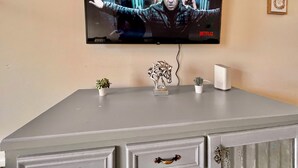 Un televisor fijado a la pared mostrando una escena de cine o programa.