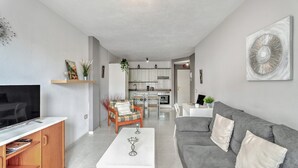 Una sala de estar moderna con un televisor de pantalla plana, un sofá gris y una mesa de centro.