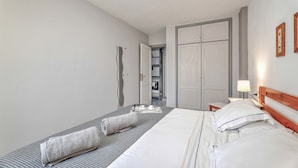 Una habitación de hotel con cama, mesita de noche con lámpara, armario y espejo.