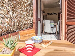 Une table en bois, sur laquelle se trouvent un pot de fleurs, une tasse à rayures, un bol et un objet emballé.
