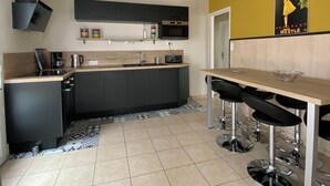 Een moderne keuken met een centraal eiland, zwarte kasten, een magnetron en een koffiezetapparaat.