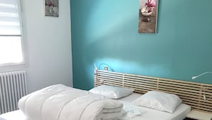 Een net opgemaakt bed met witte beddengoed en kussens, een houten hoofdbord en een klein nachtkastje.