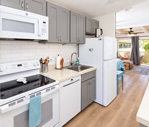 Eine moderne Küche mit weißen Geräten, grauen Schränken und einem Essbereich aus Holz.