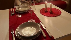 Une table à manger dressée avec des assiettes, des verres, des couverts et des bougies, ce qui indique qu’un repas a été préparé.