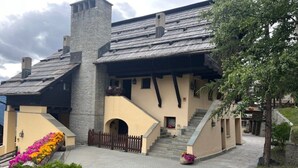 Un bâtiment doté d’une cheminée en pierre, d’un escalier et de parterres de fleurs.