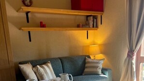 Une pièce chaleureuse avec une table préparée pour le thé, un canapé, un buffet rouge et une lampe.