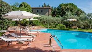 A swimming pool with lounge chairs and umbrellas, surrounded by greenery and a stone building. - Country House 'La Pineta Farm House' with Private Pool and Wi-Fi (Varna)