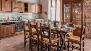 A kitchen with wooden cabinets, a dining table set for four, and a brick wall. - Country House 'La Pineta Farm House' with Private Pool and Wi-Fi (Varna)