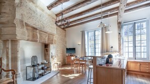 A spacious kitchen with wooden beams, a stone wall, and a large window.