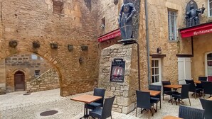 A courtyard with stone walls, outdoor seating, and a restaurant sign.