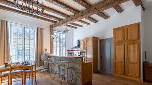 A kitchen with wooden beams, a bar area, and a dining table with chairs.
