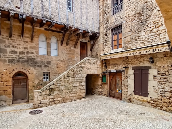 A stone building with a sign reading 'La Cour des Poètes' and 'Restaurant La Cour des Poètes.'