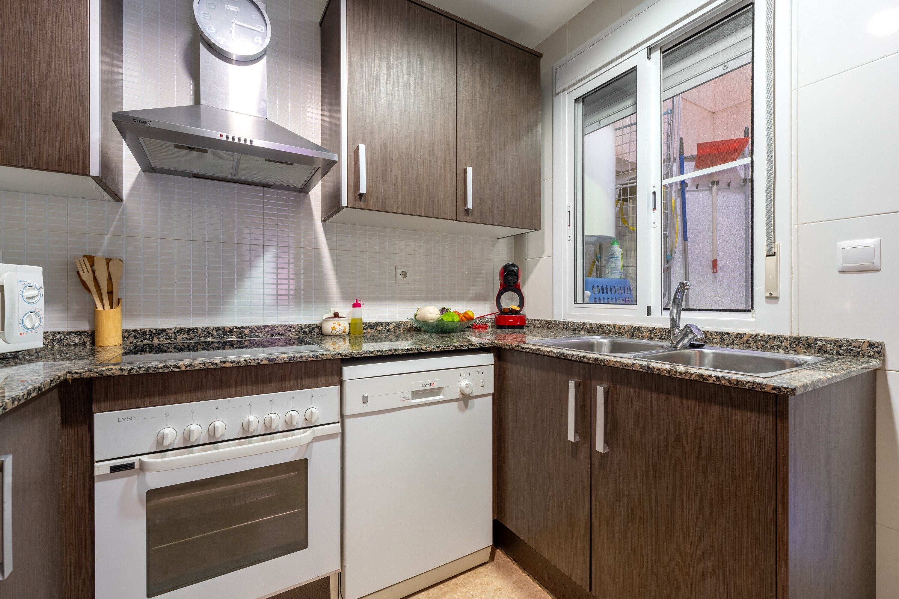 A modern kitchen with a built-in oven, dishwasher, and stainless steel sink.