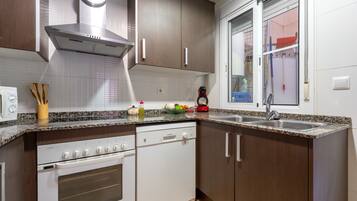 A modern kitchen with a built-in oven, dishwasher, and stainless steel sink.