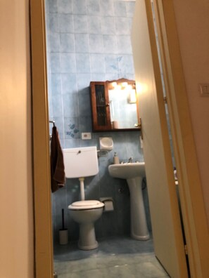 A bathroom with a toilet, sink, and mirror. - House in the Iblei (Canicattini Bagni)