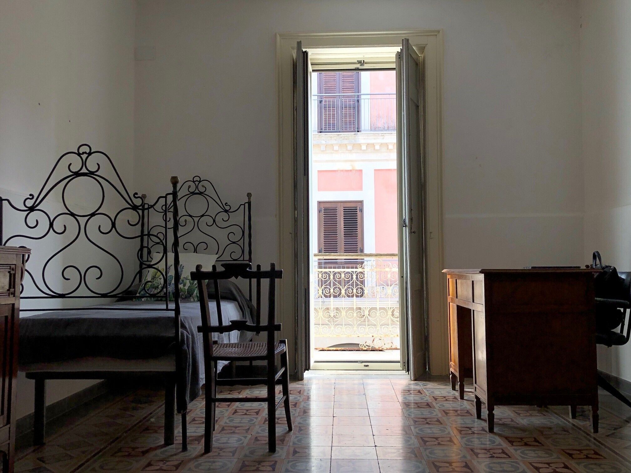 A room with a bed, a chair, a desk, and a bathroom area.