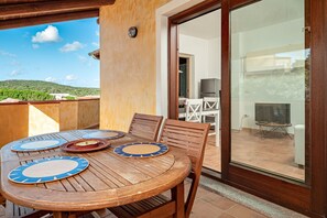 Una mesa de madera con platos azules y beige, un televisor y un patio con vistas a zonas verdes.