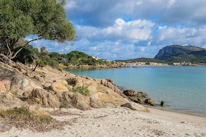 Paisaje costero con terreno rocoso, una playa de arena y una vista despejada del mar.
