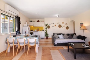 A compact living space with a dining area, kitchenette, and a sofa.
