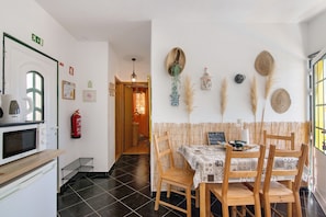 Een eethoek met een tafel voor twee personen, een magnetron en een brandblusser aan de muur.