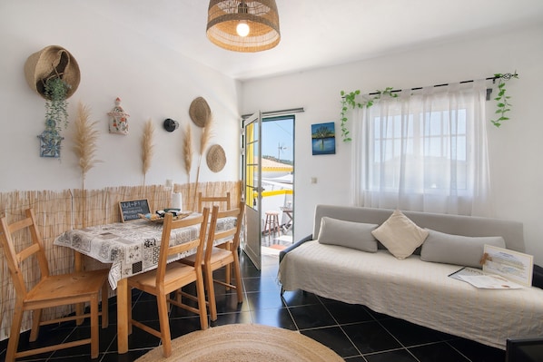 A room with a dining table, chairs, a sofa, and a bed.