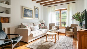 A cozy living room with a sofa, armchairs, a coffee table, and artwork on the walls.
