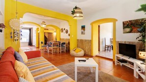 A living room with a sofa, a TV, and a dining area with chairs and a table. - Holiday Home 'Casa 1' with Shared Pool and Wi-Fi (Salir)