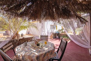 An outdoor patio with a table, chairs, a thatched roof, and draped fabric. - Holiday Home 'Casa 1' with Shared Pool and Wi-Fi (Salir)