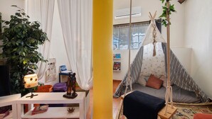 A cozy room with a bed, a hanging chair, a lamp, and a large plant. - Holiday Home 'Casa 1' with Shared Pool and Wi-Fi (Salir)