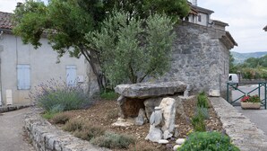 A stone building with a rustic stone wall, a tree, and a garden with lavender and other plants. - Holiday Home 'Gite De L'écurie' with Air Conditioning (Berrias-et-Casteljau)