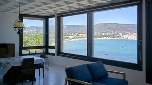 Um quarto com uma janela grande, uma mesa de jantar e uma cadeira azul.