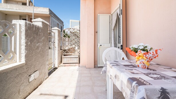 Ein Balkon mit Tisch, Stuhl und Blumenarrangement.