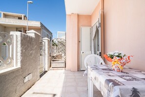 A balcony with a table, a chair, and a flower arrangement.