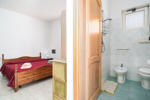 Un dormitorio con cama de madera, cómoda y baño con bidé e inodoro.
