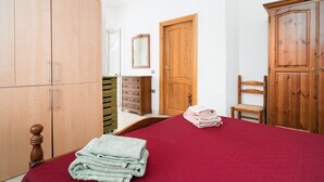 Ein Schlafzimmer mit einem Bett, einem Holzschrank, einer Kommode und einem Sessel.