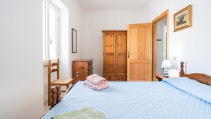 A bedroom with a bed, wooden wardrobe, chair, and a bedside table with a lamp. - Apartment 'Posada Porto' with Private Terrace (San Giovanni)