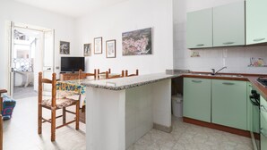 A kitchen with a dining area, a TV, and a small island. - Apartment 'Posada Porto' with Private Terrace (San Giovanni)