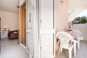 Een kamer met een bed, een houten kast, een tafel met stoelen en een schuifdeur.