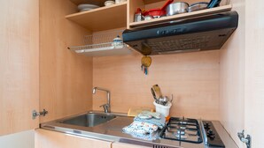 Uma cozinha compacta com pia, fogão e armários de madeira.
