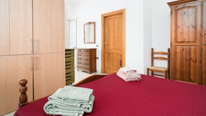 Quarto com cama, guarda-roupa de madeira, penteadeira e uma cadeira.