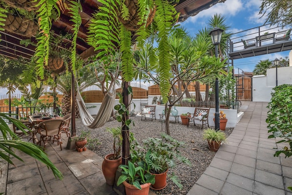 Une terrasse avec un hamac, des plantes en pot, du mobilier d’extérieur et une pergola.
