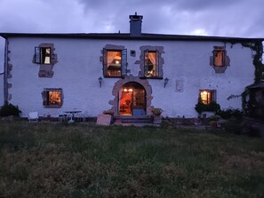 Un edificio blanco con múltiples ventanas, una entrada central en arco y asientos exteriores.