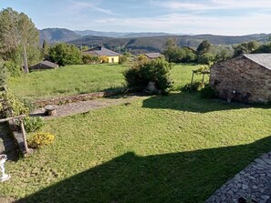 Ländliche Landschaft mit Steinhäusern, einem Steinweg und einem Wiesenfeld.