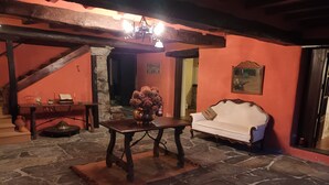 Ein Zimmer mit Steinboden, einem weißen Sofa, einem Holztisch mit einer Vase und einer Treppe.