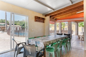 Un patio al aire libre con una mesa, sillas, techo de madera y vistas del entorno.